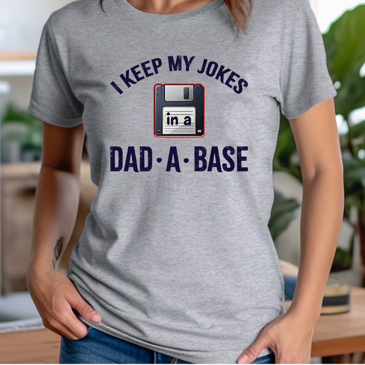 Woman in crew neck grey t-shirt featuring floppy disk pun design I keep my jokes in a dad-a-base