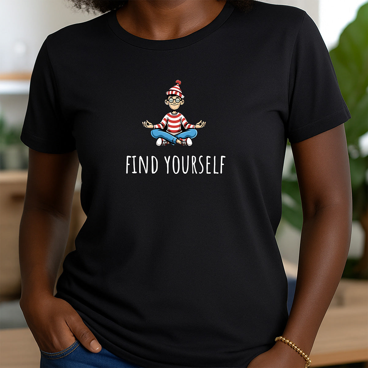 Woman wearing black crewneck shirt with meditating Waldo cartoon and Find Yourself text