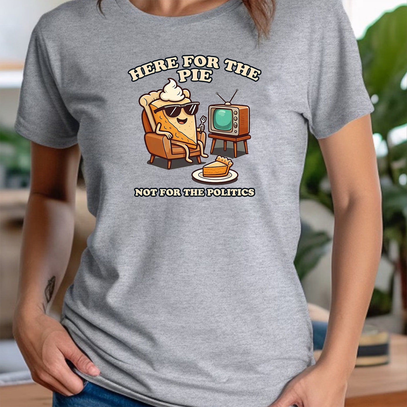 woman in crew neck gray t-shirt featuring cartoon pie slice with tv and text here for the pie not for the politics