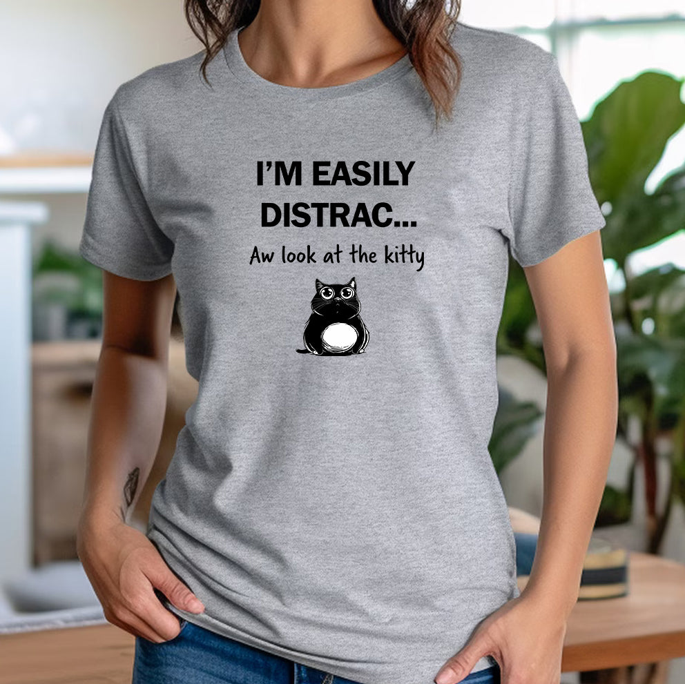 Woman wearing gray t-shirt with black cat graphic and humorous text about being distracted