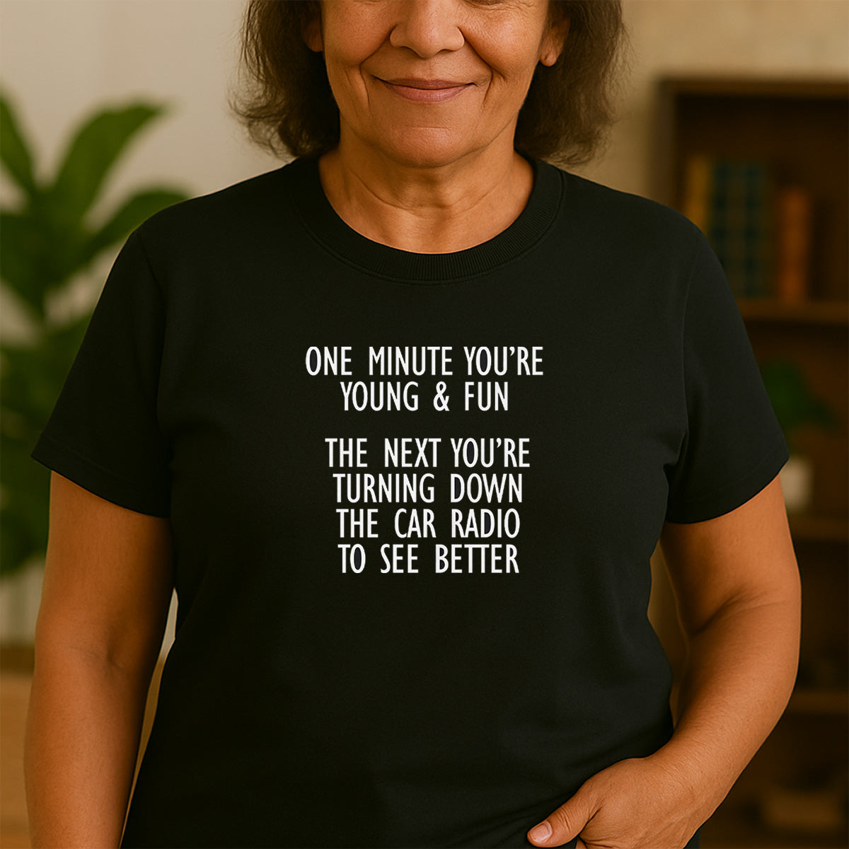 Woman wearing black crew neck t-shirt with funny quote about getting older and car radio vision joke