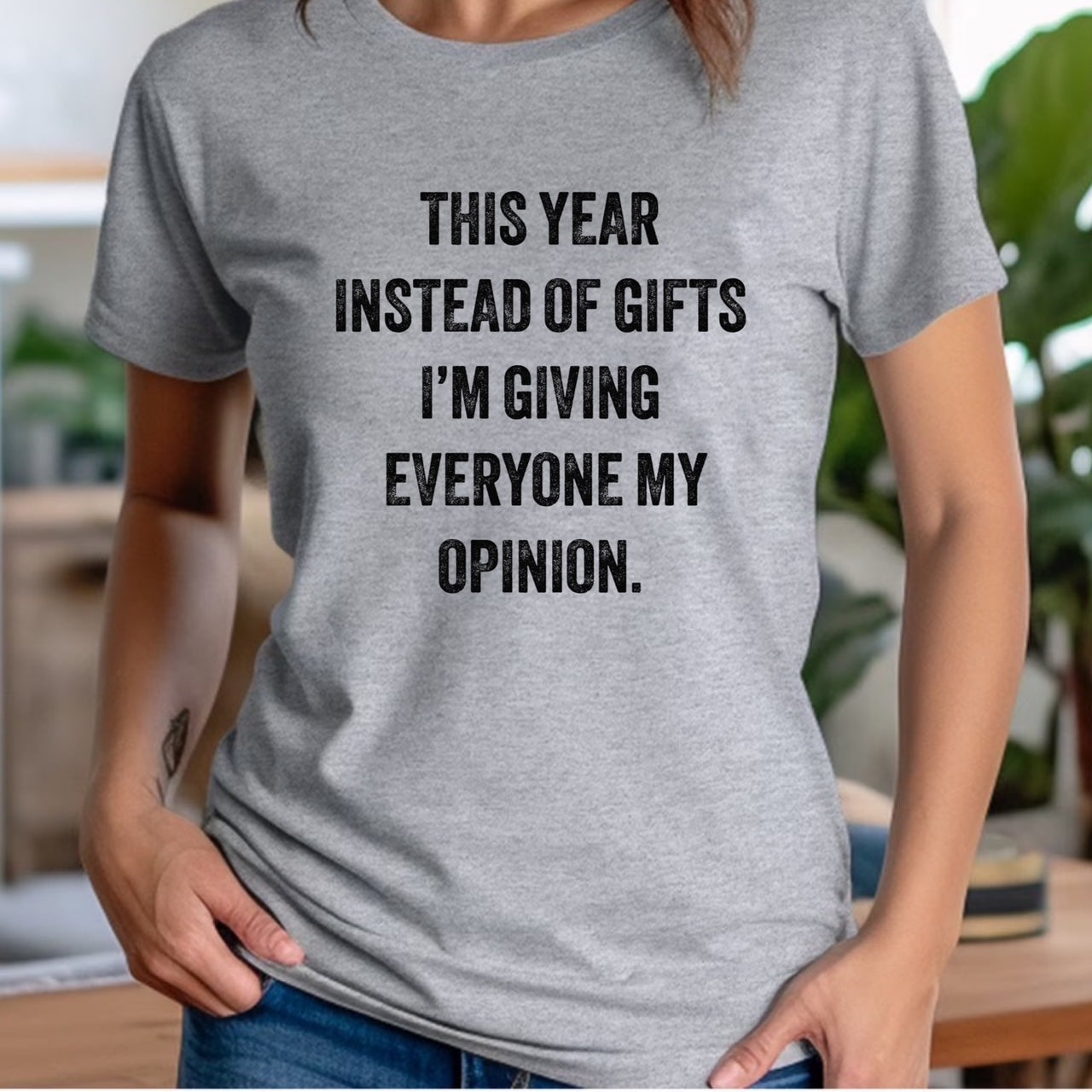 Woman in grey crewneck t-shirt featuring bold text this year instead of gifts I'm giving everyone my opinion
