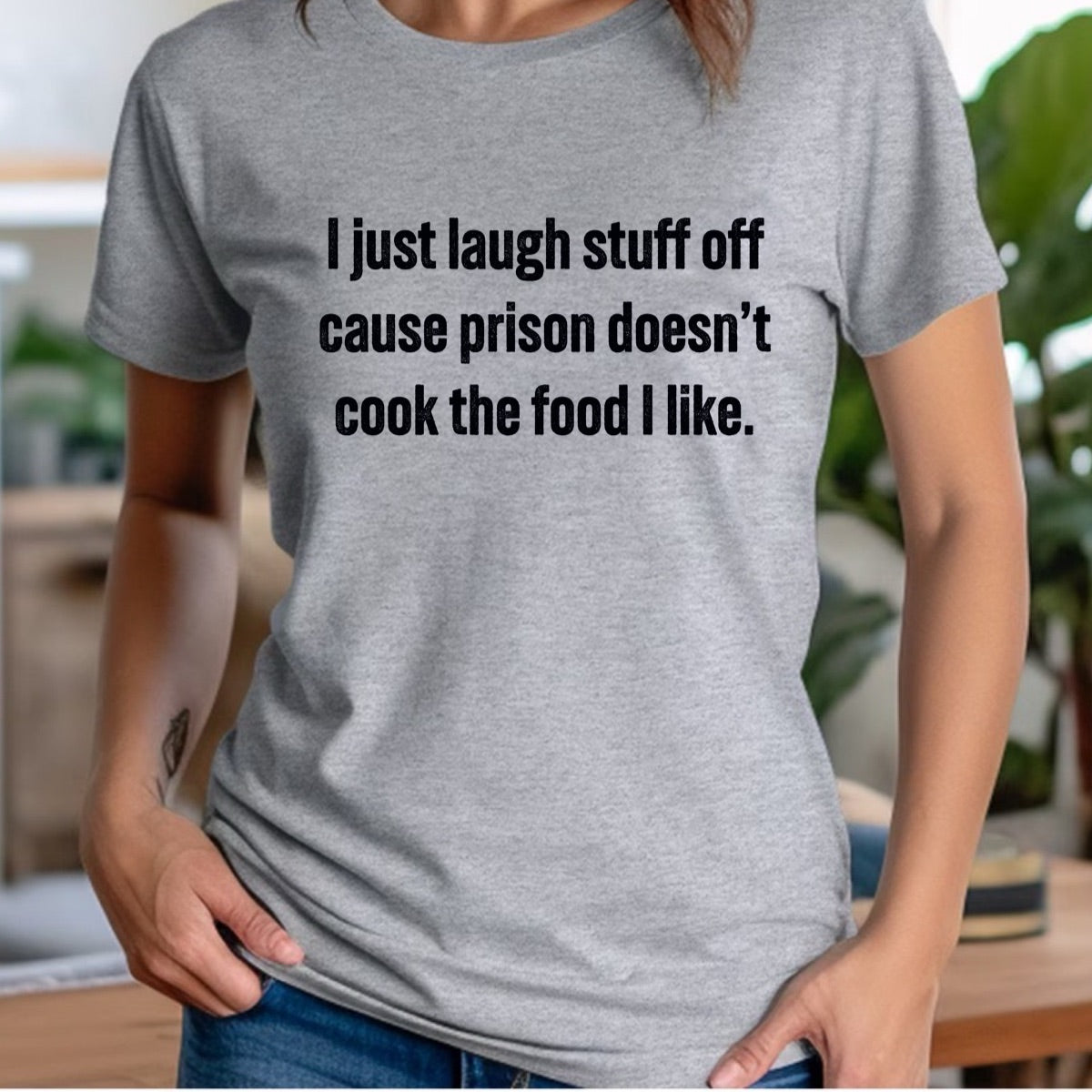 Woman in gray crewneck t-shirt with text I just laugh stuff off cause prison doesn’t cook the food I like