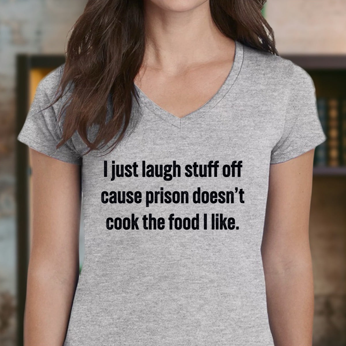 Woman wearing gray v-neck shirt with text I just laugh stuff off cause prison doesn’t cook the food I like