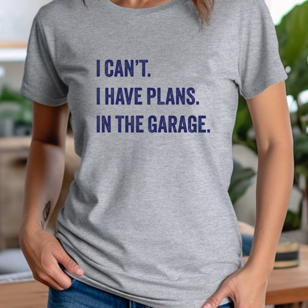 Woman in casual crew neck grey t-shirt with navy text I can’t I have plans in the garage
