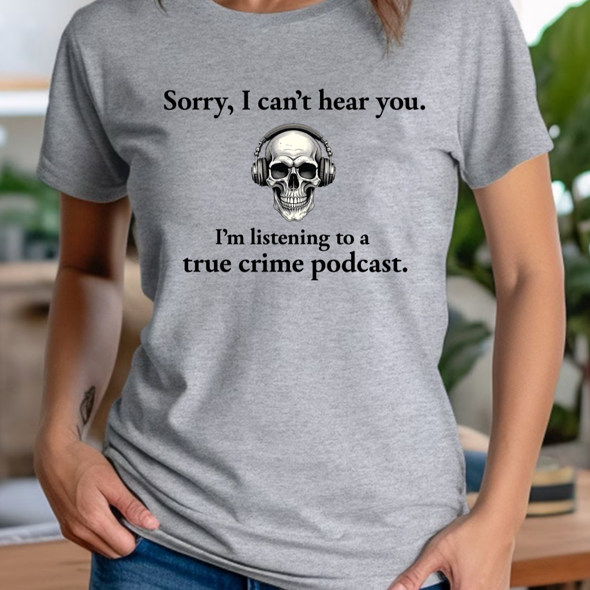 Women’s heather gray tee with skull wearing headphones and true crime podcast quote, indoor mockup