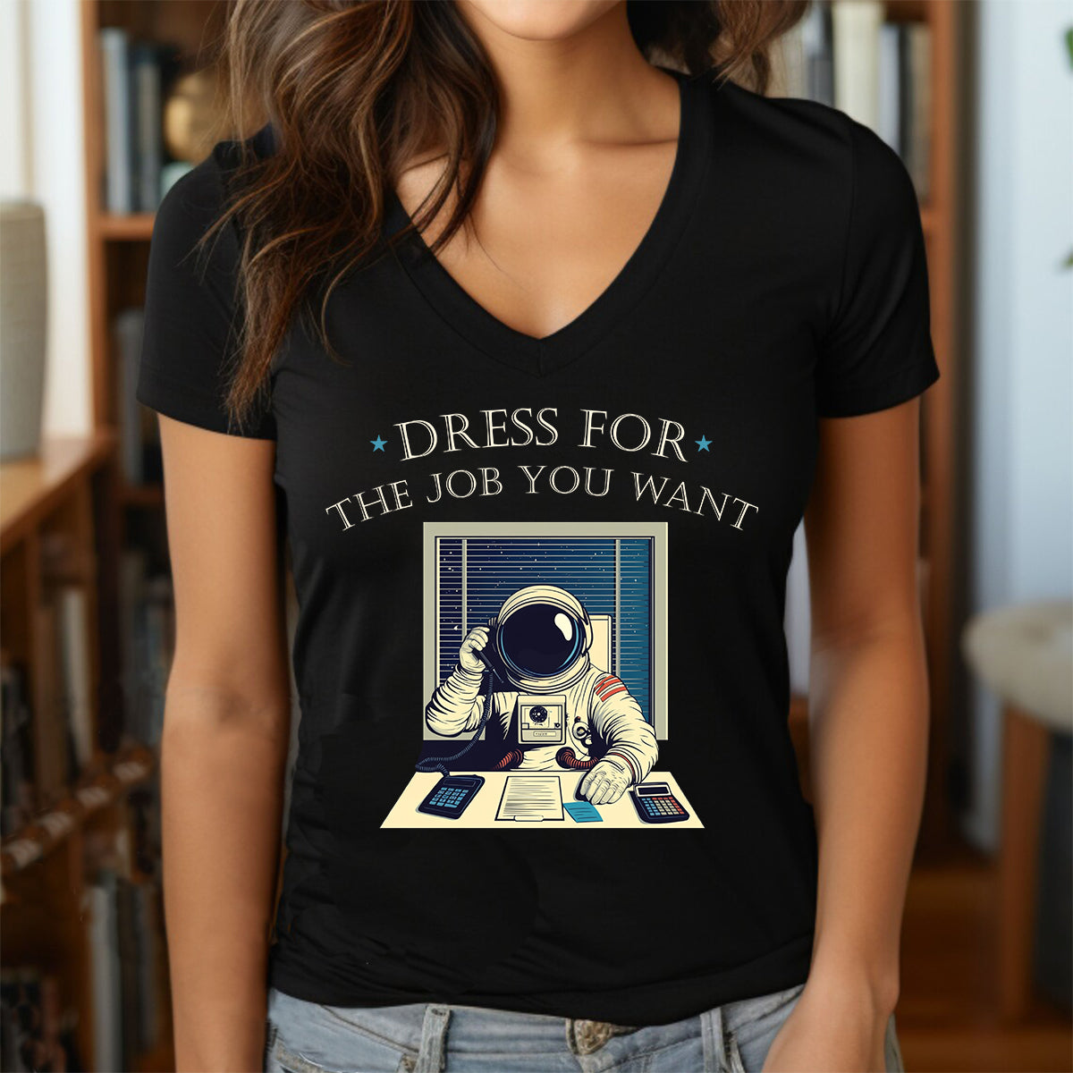 Woman wearing black v-neck t-shirt with astronaut office desk design and text dress for the job you want