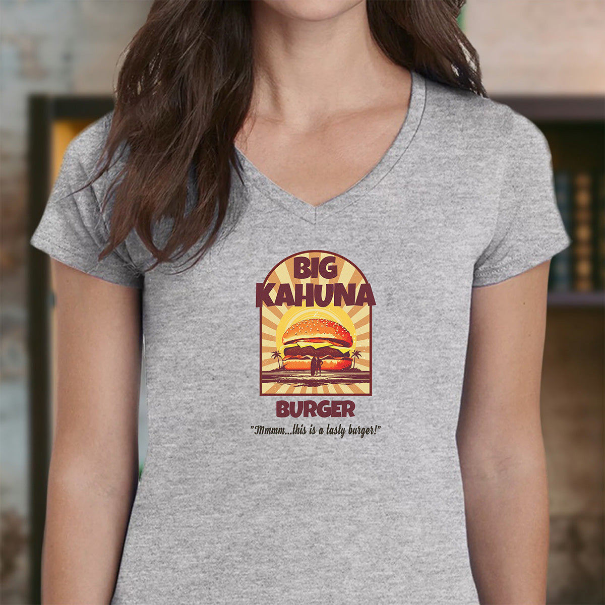 Woman in grey v-neck t-shirt with vintage Big Kahuna Burger design and palm tree silhouette