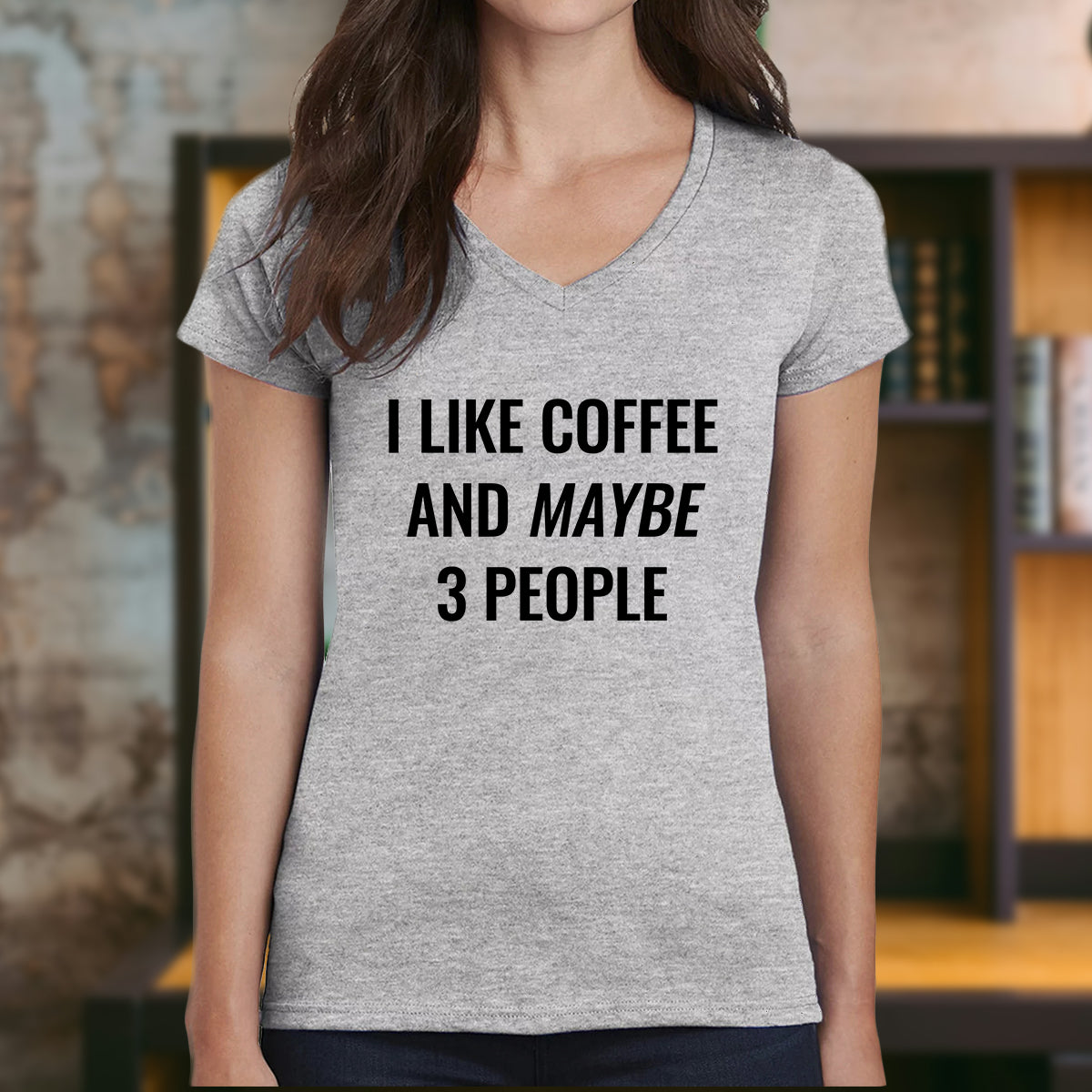 Woman wearing grey v-neck funny coffee t-shirt that says I like coffee and maybe 3 people