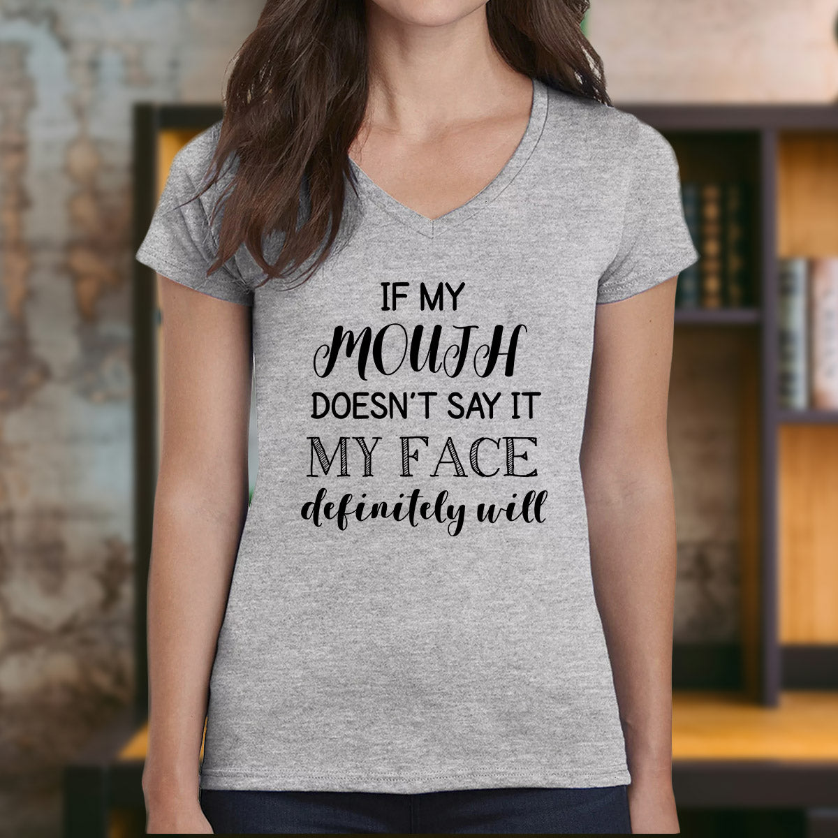 Woman wearing v-neck grey shirt with black quote "If my mouth doesn’t say it my face definitely will."
