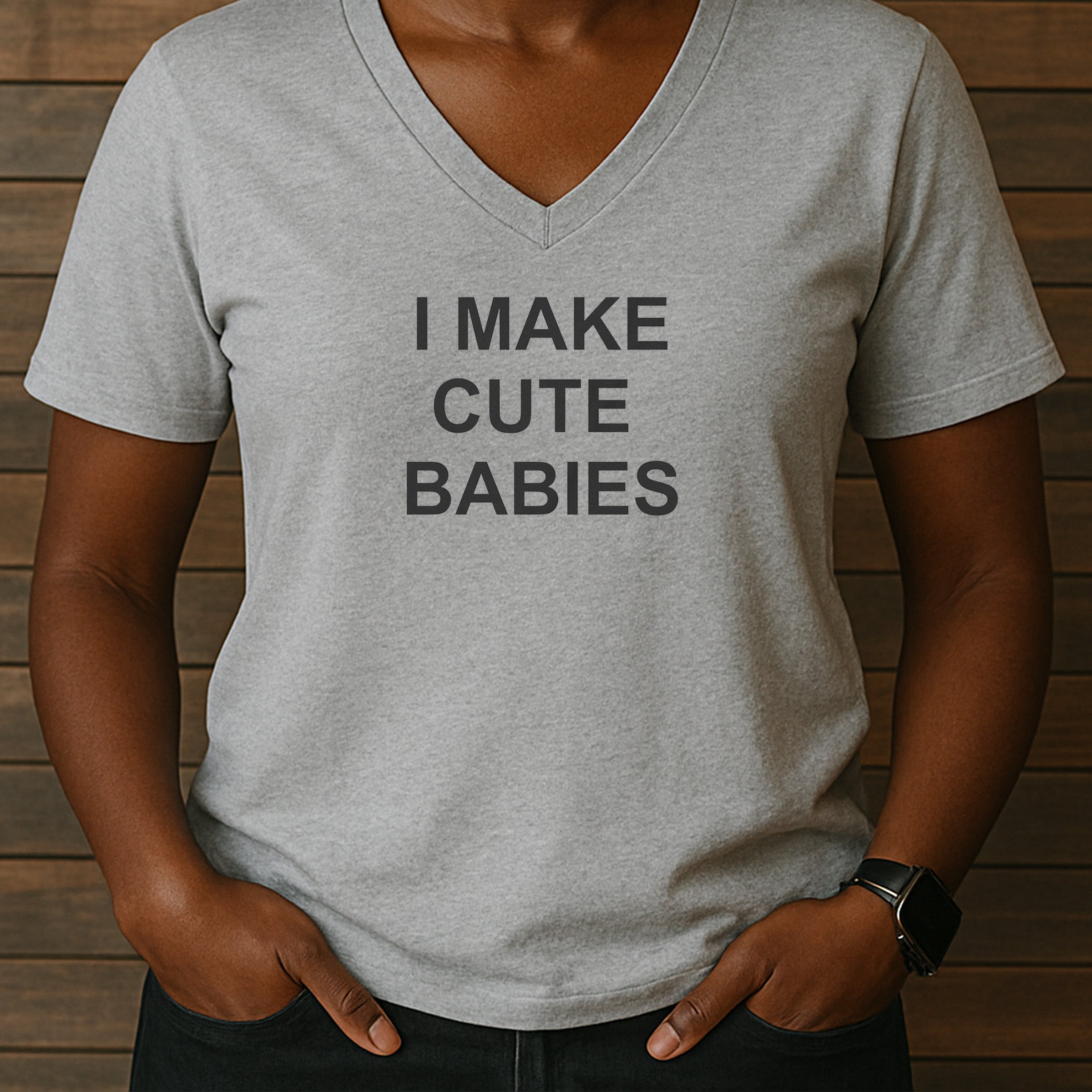 Woman in heather gray V-neck tee reading I MAKE CUTE BABIES, comfy funny parent shirt styled casual