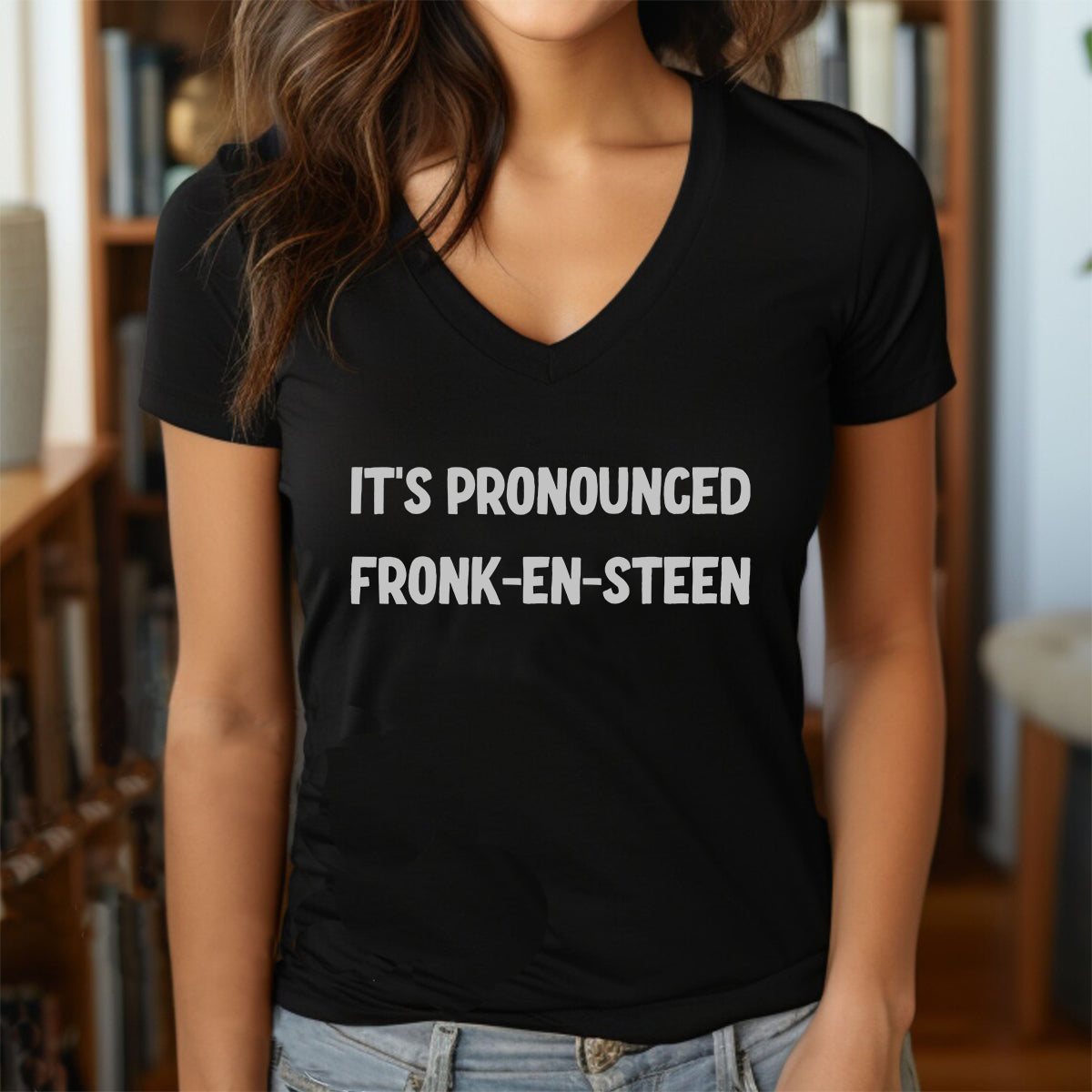 Woman wearing a black V-neck Halloween t-shirt with white text It’s Pronounced Fronk-en-Steen