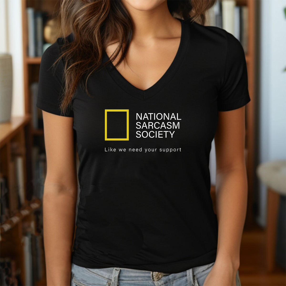 Woman in black v-neck shirt featuring National Sarcasm Society text and slogan Like we need your support