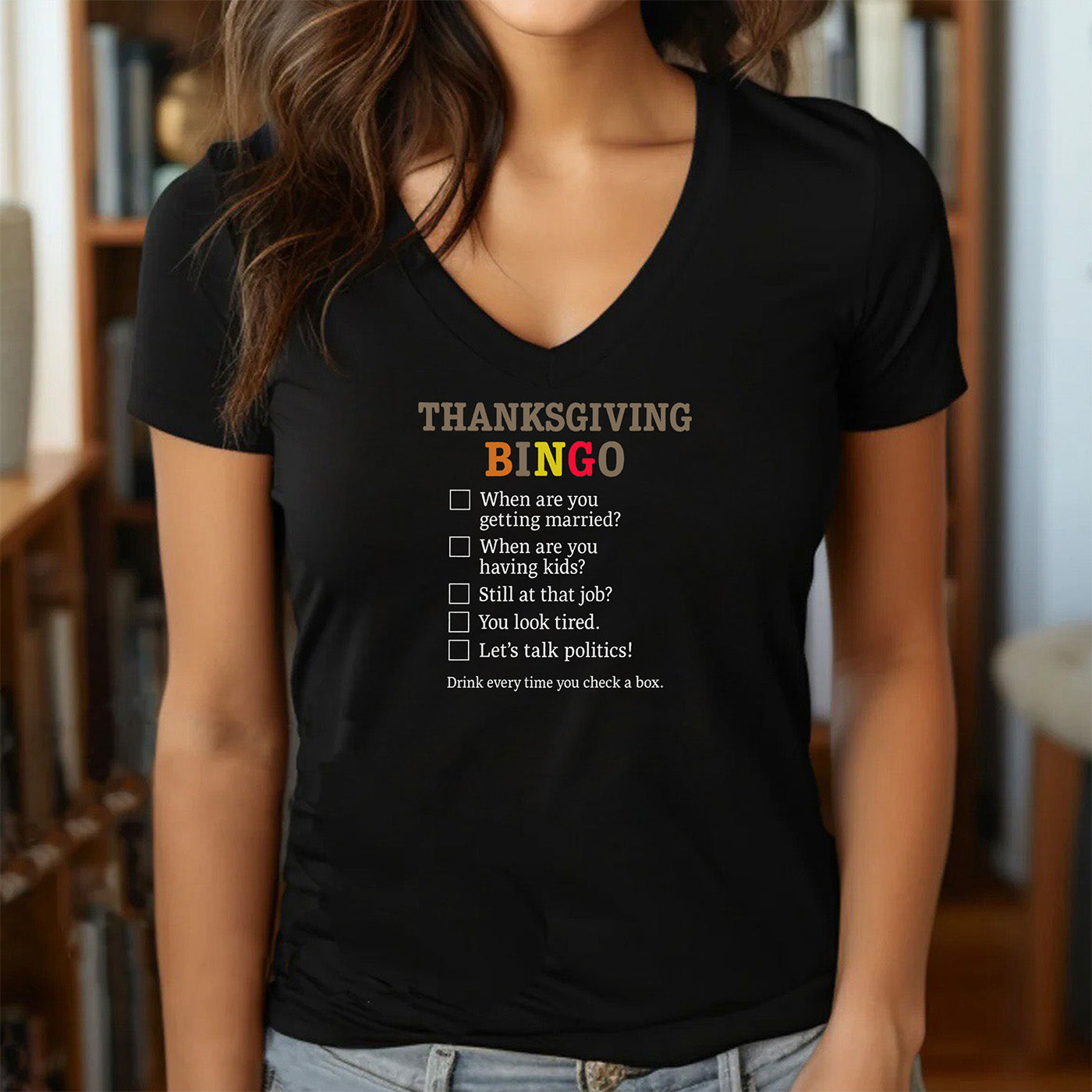 woman wearing v-neck black t-shirt with thanksgiving bingo design and humorous family question list